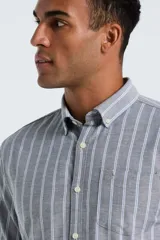 Camisa de manga larga confeccionada en tejido Oxford, con diseño de rayas verticales en tonos gris y azul claro. Presenta cuello abotonado, cierre frontal con botones y un bolsillo en el pecho.