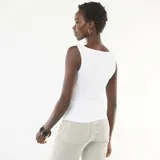 Camiseta sin mangas de color blanco, con escote asimétrico y detalle de joya dorada en el hombro. Presenta un ajuste al cuerpo con frunces laterales.