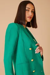 Blazer verde en crepe con solapas de muesca y cierre frontal con doble botonadura dorada.