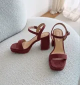 Sandalias de cuero color uva, con taco ancho, plataforma delantera y tira en el tobillo con hebilla ajustable.