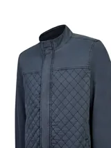 Chaqueta de gabardina de algodón color gris oscuro, con cuello alto, cierre frontal con solapa y bolsillos con diseño acolchado romboidal en el frente.