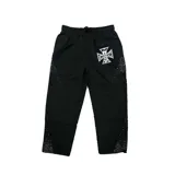 Pantalón de nylon color negro, con cintura elástica y cordón de ajuste. Presenta un estampado gráfico de cruz con la palabra 'Emotion' en la parte superior y detalles de tachas brillantes en los laterales.