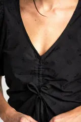 Blusa negra de algodón con diseño bordado sutil, escote en V y cordón ajustable fruncido en el centro del frente. Mangas cortas abullonadas.