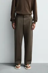 Pantalón de corte relaxed fit confeccionado en tejido de mezcla de algodón y lino. Presenta cintura con pliegues frontales, bolsillos laterales y bolsillos traseros de doble vivo. Cierre frontal con cremallera y botón.