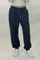 Pantalon deportivo tipo babucha de color beige, con cintura elástica ajustable mediante cordón y puños elásticos en los tobillos.