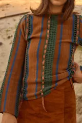 Sweater de lana de cordero con cuello a la base y manga larga. Presenta un diseño de franjas verticales combinando tejido de punto con detalles en crochet y cintas de lúrex brillante.