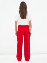 Pantalón de corte recto y tiro alto, color rojo, con costuras decorativas en contraste y cierre frontal con cremallera expuesta.