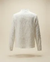 Camisa de algodón color blanco, con diseño romántico que presenta alforzas verticales y una guarda central con puntilla. Posee cuello ligeramente fruncido, mangas largas con volumen y botones frontales con detalle de cruz bordada en color chocolate.