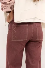 Jeans de corte recto y tiro medio color gris oscuro, con costuras en contraste y detalles de bordado geométrico en el bajo.