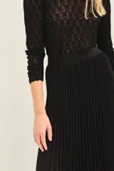 Falda midi plisada de color negro, con cintura elástica para un ajuste cómodo.