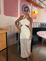 Vestido largo de crochet color crudo, con escote halter, espalda descubierta y aberturas laterales en la cintura.