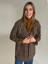 Sobrecamisa de lana con estampado de cuadros en tonos tierra, corte oversize, cuello camisero, cierre frontal de botones y bolsillos delanteros con solapa.