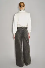 Pantalon de denim de corte amplio y tiro medio, color gris oscuro con efecto lavado. Presenta bordados decorativos con pedrería a lo largo de los laterales de las piernas.