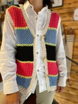 Chaleco tejido a mano de hilo de algodón, con diseño de franjas horizontales en colores fucsia, celeste, negro y detalles en amarillo flúor, escote en V y cierre frontal con botones.