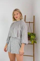 Conjunto de dos piezas en color crema, compuesto por un buzo de cuello alto, mangas largas abullonadas y ajuste en la cintura, junto con un short de tiro alto con terminaciones al corte.