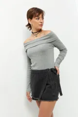 Short pollera de jean prelavado color negro, con lazo en uno de sus laterales y detalle de flecos en las terminaciones.