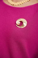 Broche dorado con forma de espiral, incrustaciones de strass y una perla central.