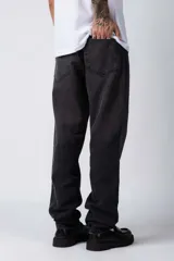 Jean de corte mom oversize, color negro lavado, con diseño de cinco bolsillos y cierre frontal con botón y cremallera.