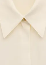 Camisa de seda 100% color marfil, de corte recto, con cuello camisero clásico y cierre frontal de botones ocultos.