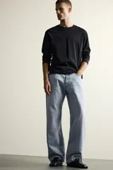Jeans de denim de algodón en color azul con efecto desgastado, tiro medio y corte recto de ajuste holgado (loose fit). Cuenta con diseño clásico de cinco bolsillos y cierre frontal con cremallera y botón.