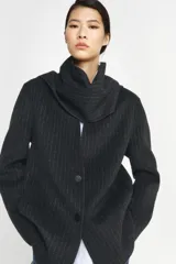 Blazer de corte recto confeccionado en mezcla de lana con estampado de rayas verticales. Presenta cuello redondo con bufanda incorporada en el mismo tejido, manga larga, bolsillos delanteros y cierre frontal con botones.
