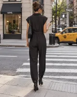 Mono largo sin mangas color beige, con cuello solapa, cierre cruzado con botones metálicos y cinturón ajustable con hebilla. Cuenta con bolsillos superiores con solapa.