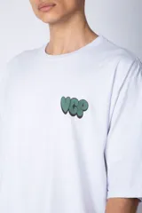 Remera de corte oversize color blanco, con cuello redondo y mangas cortas. Presenta un pequeño logo estampado en el pecho y un diseño gráfico grande en la espalda que incluye la frase 'Good Children' e ilustraciones de un ángel y llamas.
