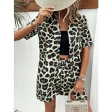Conjunto de dos piezas compuesto por una camisa de manga corta con cuello italiano y cierre frontal de botones, y un short con cintura elástica y bolsillos laterales. Ambas prendas presentan un diseño estampado de animal print.