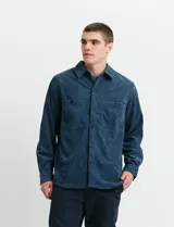 Sobrecamisa de pana color marrón, con manga larga, cierre frontal con botones y dos bolsillos frontales con solapa y botón.