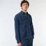 Camisa de denim azul con diseño de rayas verticales finas y blancas, manga larga con puños ajustables, cierre frontal de botones y dos bolsillos de parche con solapa en el pecho.