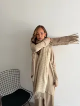 Bufanda de tejido suave con diseño de cuadros grandes en tonos negro y beige, terminada con flecos en los extremos.