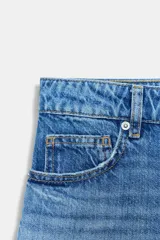 Shorts de denim de tiro medio, color celeste claro con efecto lavado y desgaste sutil. Diseño de cinco bolsillos con cierre frontal de cremallera y botón metálico.