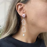 Aros colgantes con pasador y avíos metálicos plateados. Presentan un círculo naranja, una figura abstracta transparente con borde rosa, un círculo rosa con un strass y una pieza colgante naranja.
