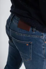 Pantalón de jean azul de corte slim, con diseño clásico de cinco bolsillos, trabillas para cinturón y cierre frontal con botón y cremallera.