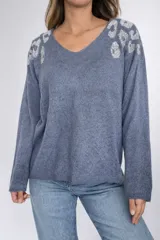 Buzo de punto oversize color azul, con escote en V y detalles de piedras plateadas en los hombros que forman un diseño tipo print.