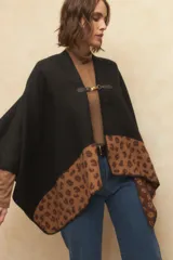 Poncho negro con estampado animal print en el borde inferior y cierre con alamar dorado.