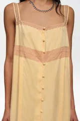 Vestido midi de línea A color amarillo, confeccionado en mezcla de lyocell y viscosa, con botones frontales, escote cuadrado y tirantes finos. Presenta detalles de encaje en contraste y mini tablas verticales en el frente.