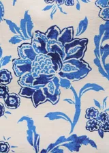 Top corto de tela color crema con estampado floral azul, de breteles anchos y escote cuadrado.