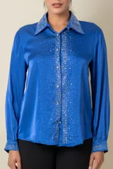 Camisa color crema de satén italiano con cuello clásico, cierre frontal con botones y mangas largas. Presenta apliques de strass en cuello, solapa y puños.