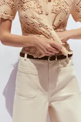 Pantalón de jean color crudo, de tiro alto, corte wide leg cropped y cinturón marrón.