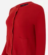 Cardigan de punto color celeste, con mangas largas, cierre frontal de botones y dos bolsillos delanteros. Presenta acabado canelado en el escote y los puños.