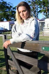Sweater de lana merino gris con detalles bordados a mano de colores en el canesú y en las mangas. Presenta cuello redondo, volados decorativos y diseño de rombos con efecto 3D.