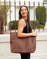 Bolso tipo tote de cuero vacuno color marrón caoba, con diseño artesanal que presenta costuras decorativas en el borde superior y asas fijas de hombro.