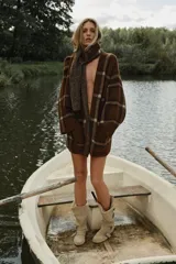 Abrigo corto de punto abierto con bufanda integrada, manga larga y bolsillos delanteros de plastrón. Presenta un diseño de cuadros en tonos marrones.