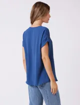 Blusa de crepe color blanco, con cuello redondo a la base y mangas cortas con detalle de presilla y botón en el borde.