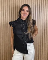 Musculosa de jean celeste sin mangas, con cuello alto fruncido, cierre frontal con botones y detalles de volados en las sisas y a lo largo de la botonera.