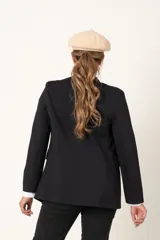 Blazer color camel de corte entallado, con doble botonadura dorada y solapas de muesca.