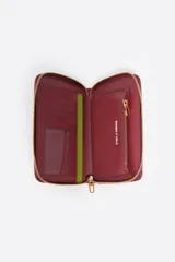 Billetera mediana de estructura rígida en color marrón topo, con cierre perimetral de cremallera y tirador decorativo de cordón. Presenta el logo de la marca aplicado en letras metálicas doradas en el frente.