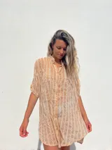 Vestido camisero color beige con bordado vertical en color blanco, de corte recto, cuello mao y mangas cortas con trabilla.