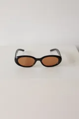 Lentes de sol con armazón ovalado de color negro y cristales tonalidad marrón. Presentan un detalle metálico en forma de estrella en las patillas.